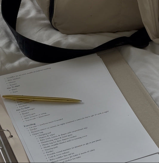 nursery checklist with a gold pen on a white surface, with a beige bag in the background.